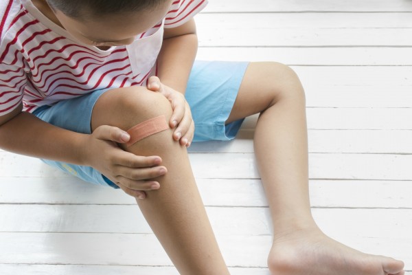 Criança com curativo no joelho